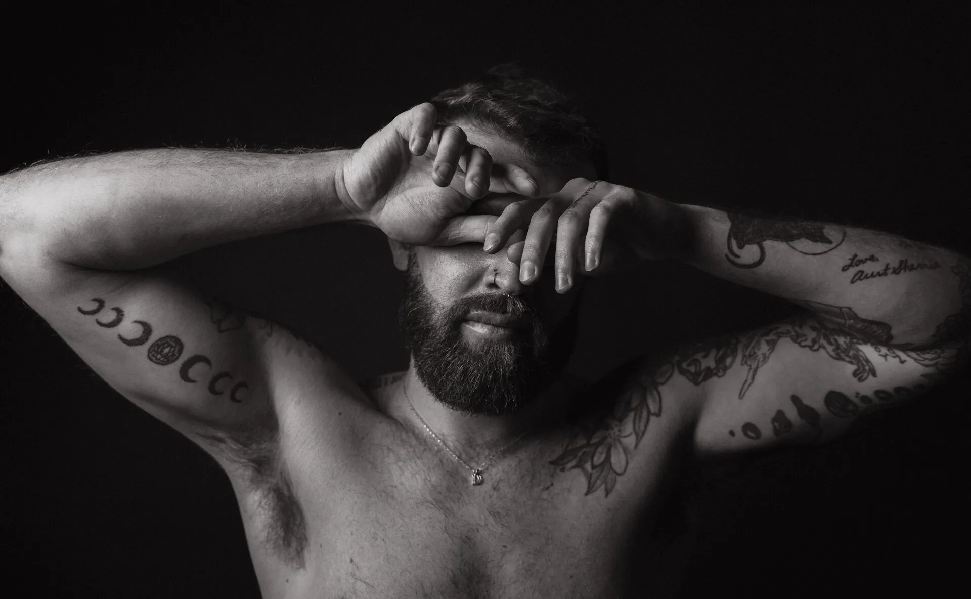 Black and white portrait of a tattooed man in the studio